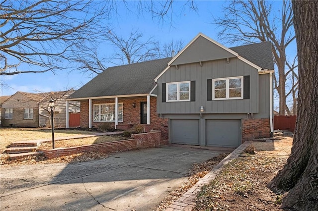 split level home featuring a garage, concrete driveway, brick siding, and a shingled roof