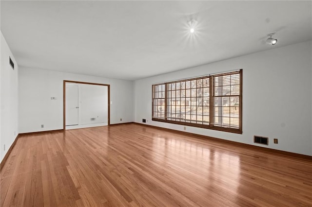 unfurnished room featuring light wood-style flooring, visible vents, and baseboards