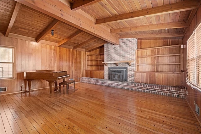 unfurnished living room featuring lofted ceiling with beams, visible vents, wood walls, and hardwood / wood-style flooring