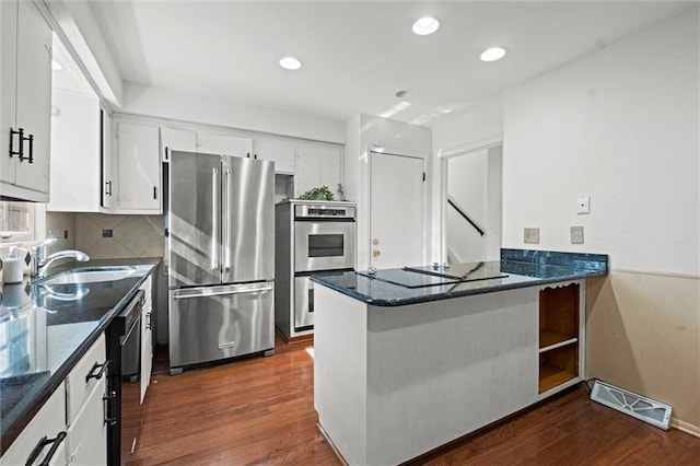 kitchen featuring dark wood-style floors, black appliances, a sink, and visible vents