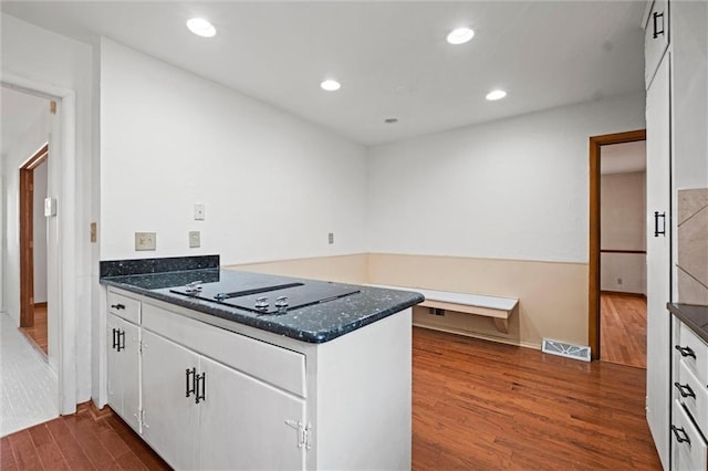 kitchen with visible vents, dark wood-style flooring, a peninsula, black electric stovetop, and white cabinetry