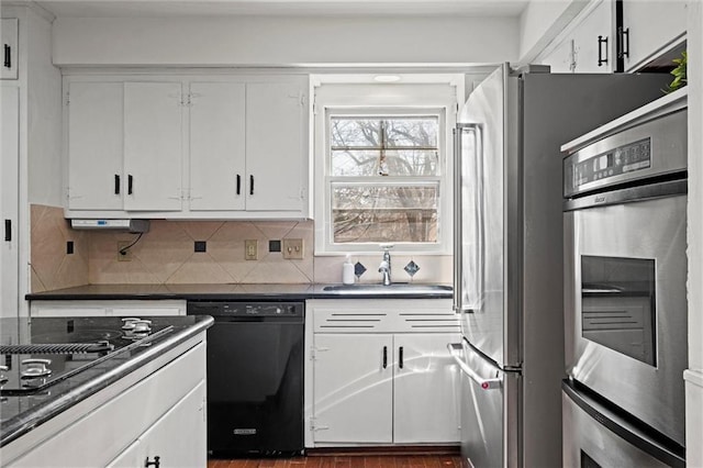 kitchen featuring tasteful backsplash, dark countertops, white cabinets, a sink, and black appliances