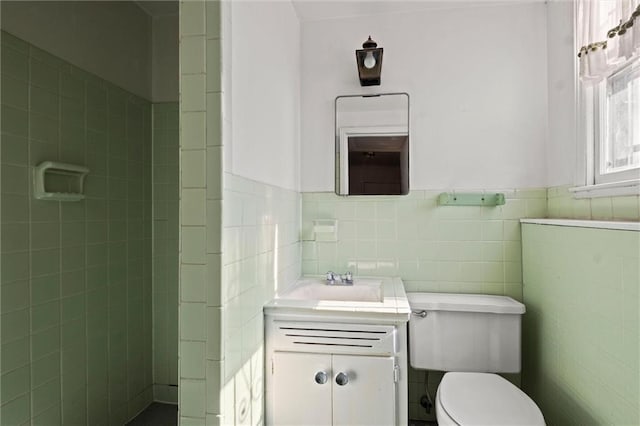 bathroom with a wainscoted wall, vanity, toilet, and tile walls