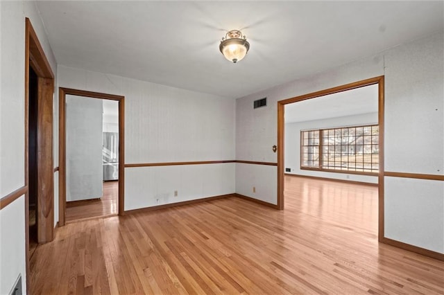 spare room with baseboards, visible vents, and light wood finished floors