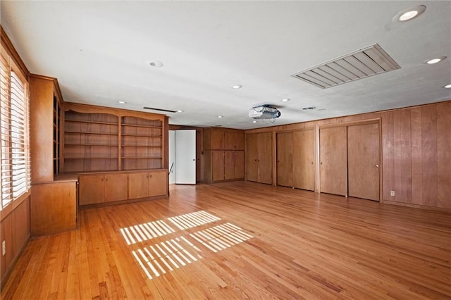 empty room with wooden walls, recessed lighting, and light wood-style floors