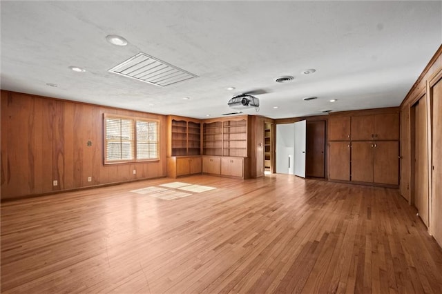 spare room featuring light wood finished floors, wooden walls, and visible vents