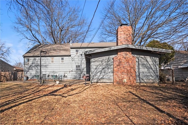 back of house with a patio, a chimney, and fence