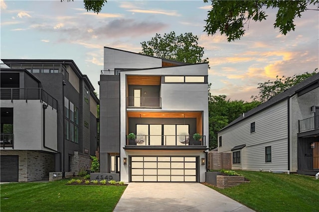 contemporary home featuring concrete driveway, an attached garage, a front yard, and stucco siding