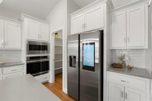 kitchen featuring stainless steel appliances, tasteful backsplash, light countertops, white cabinetry, and light wood-type flooring