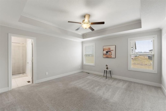 spare room with ornamental molding, a raised ceiling, and light carpet