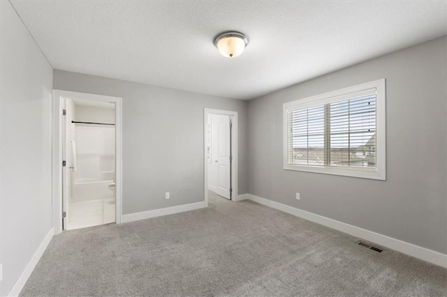 unfurnished bedroom with light carpet, connected bathroom, visible vents, and baseboards