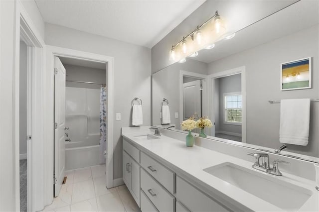 bathroom featuring double vanity, shower / bath combo, a sink, and baseboards