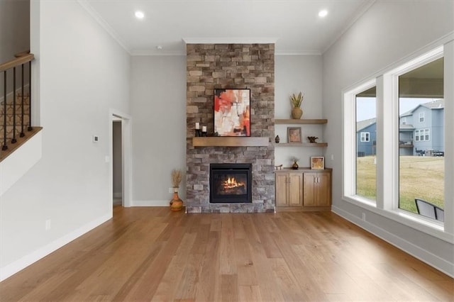 unfurnished living room featuring a fireplace, baseboards, ornamental molding, stairway, and light wood finished floors