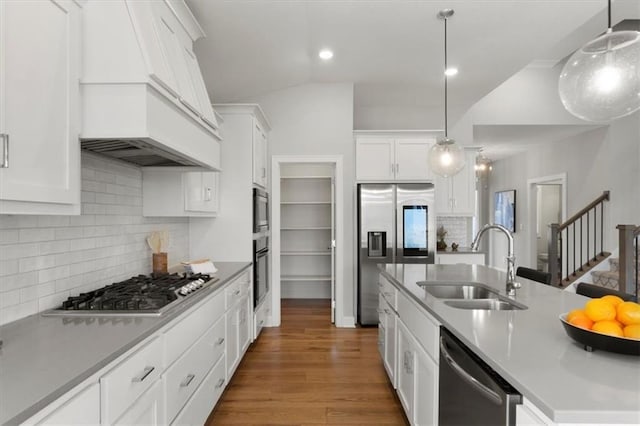kitchen featuring stainless steel appliances, a sink, custom range hood, white cabinetry, and recessed lighting