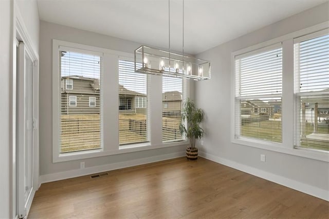 unfurnished dining area featuring plenty of natural light, baseboards, and a chandelier
