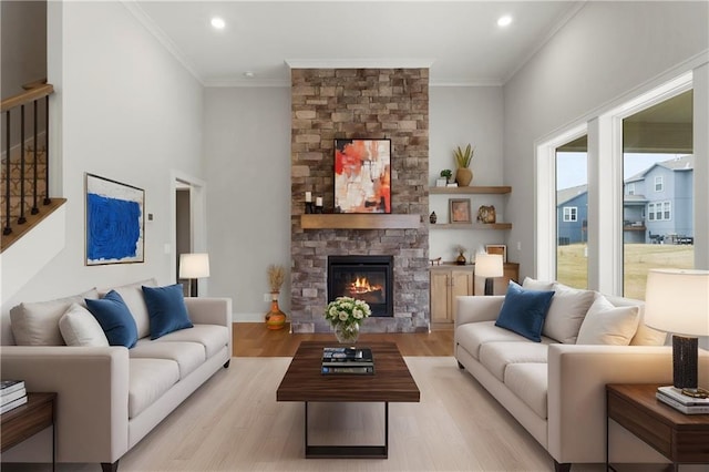 living area with crown molding, a stone fireplace, stairs, light wood finished floors, and recessed lighting