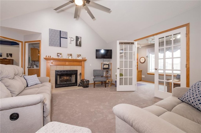 carpeted living room featuring high vaulted ceiling, ceiling fan, french doors, and a tiled fireplace