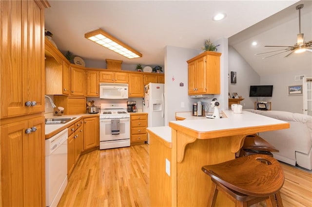 kitchen featuring kitchen peninsula, hanging light fixtures, sink, white appliances, and a kitchen breakfast bar