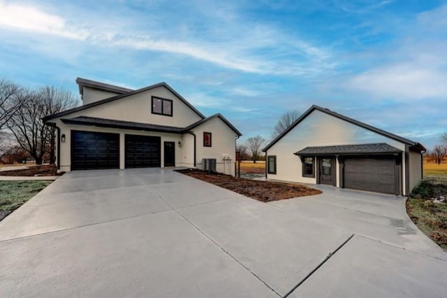 view of front of house featuring driveway, an attached garage, and central AC