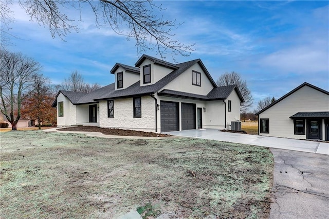 view of front of home featuring a garage, a shingled roof, concrete driveway, central air condition unit, and brick siding