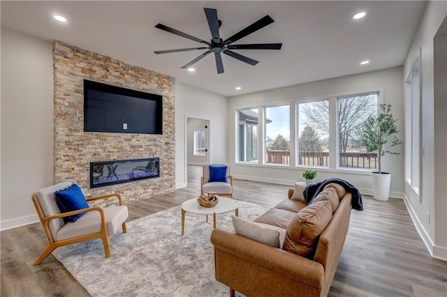 living area featuring a fireplace, baseboards, wood finished floors, and recessed lighting