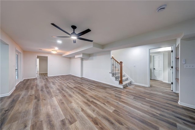 interior space with a ceiling fan, wood finished floors, baseboards, and stairs