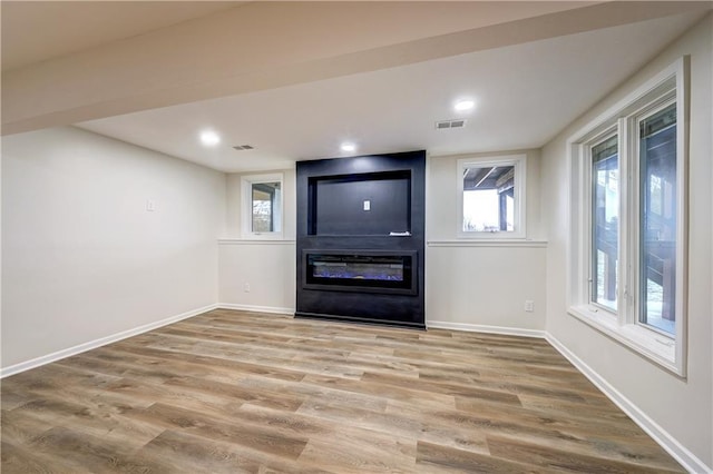 entryway featuring a large fireplace, baseboards, and wood finished floors