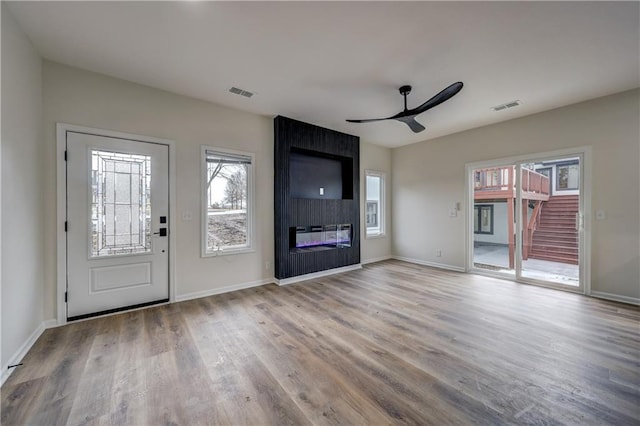 unfurnished living room featuring a ceiling fan, a fireplace, visible vents, and wood finished floors