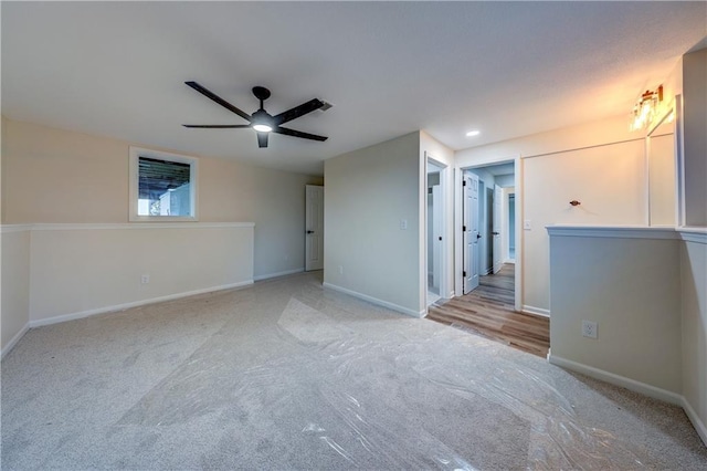 empty room featuring light carpet, ceiling fan, and baseboards