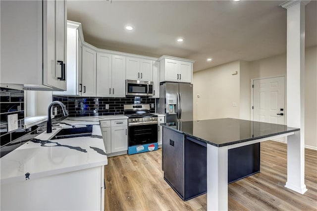 kitchen featuring appliances with stainless steel finishes, a sink, light wood-style flooring, and a kitchen island