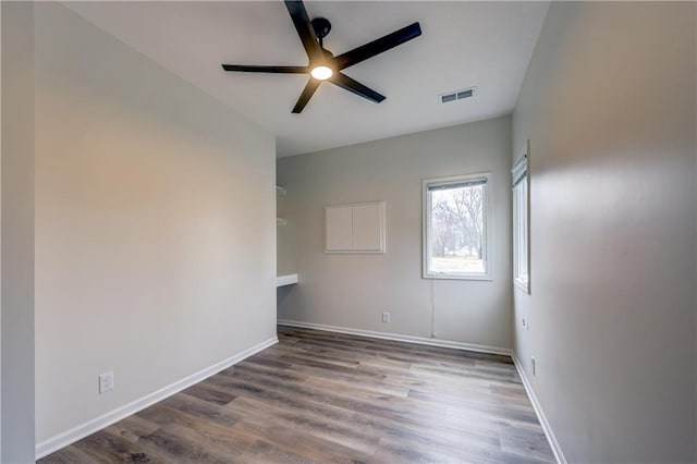 empty room featuring a ceiling fan, baseboards, visible vents, and wood finished floors