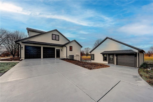 view of front of house with concrete driveway, an attached garage, and central AC unit