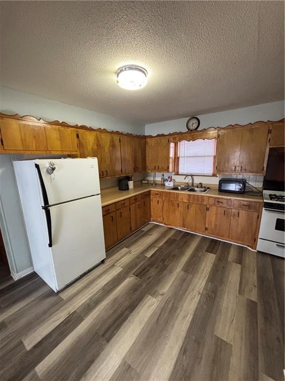 kitchen with white appliances, dark hardwood / wood-style floors, sink, and a textured ceiling