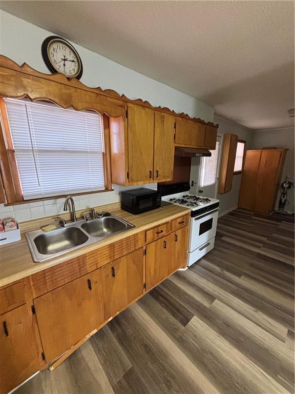 kitchen with sink, white range with gas stovetop, a textured ceiling, and dark wood-type flooring