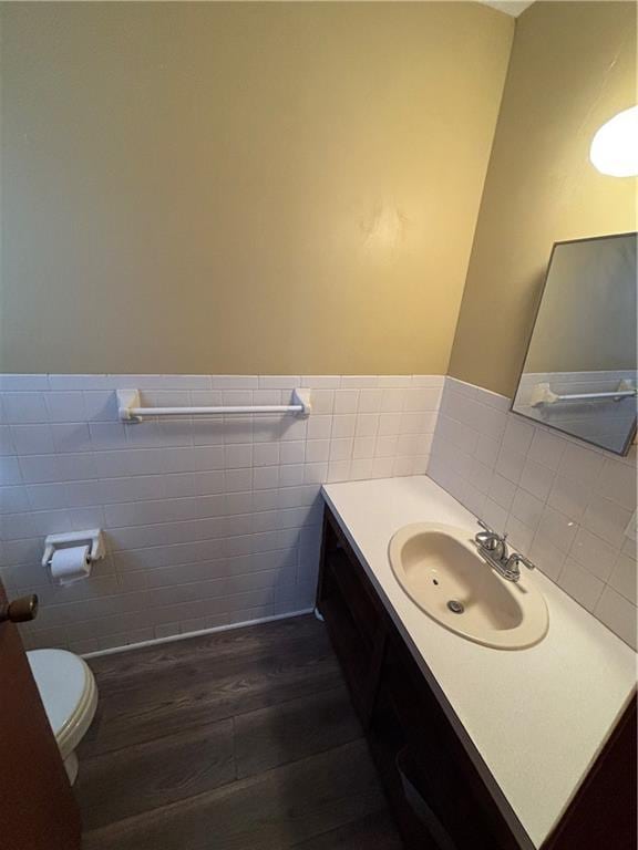 bathroom featuring vanity, toilet, wood-type flooring, and tile walls