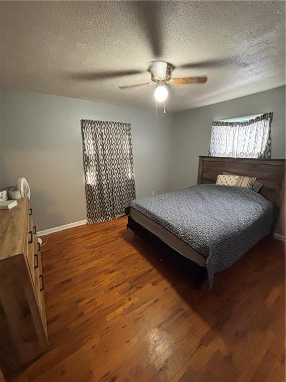 bedroom with dark wood-type flooring, ceiling fan, and a textured ceiling