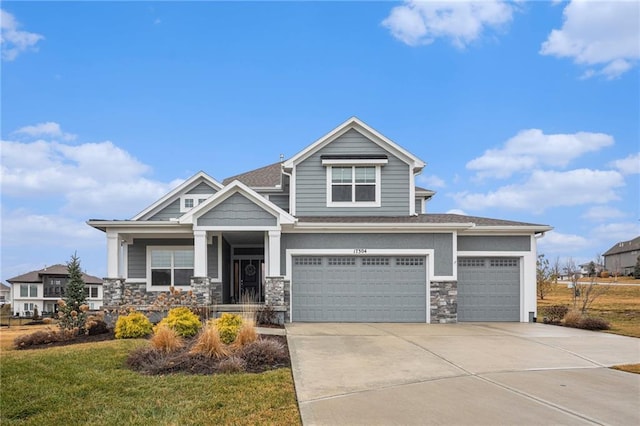 view of front facade with driveway, stone siding, an attached garage, and a front yard