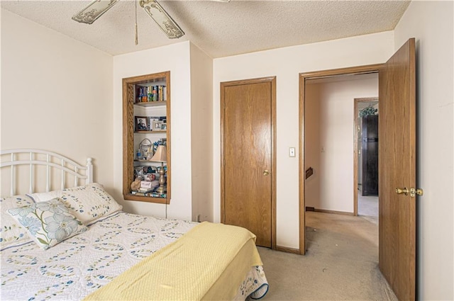 bedroom featuring freestanding refrigerator, light colored carpet, and a textured ceiling