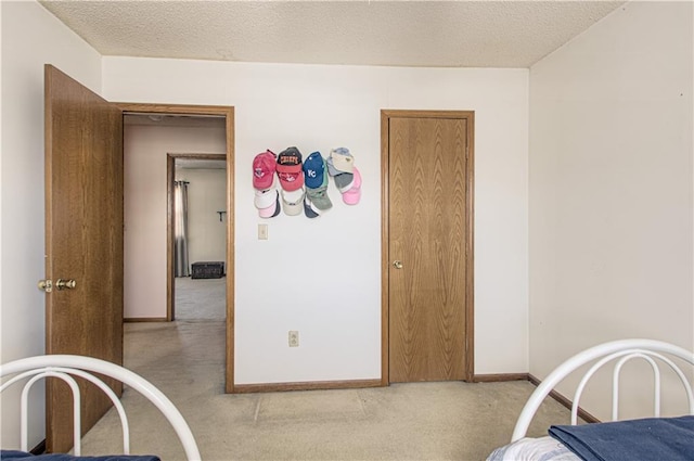 bedroom with light carpet, baseboards, and a textured ceiling