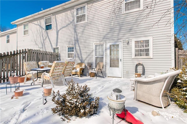 snow covered house with a patio and fence