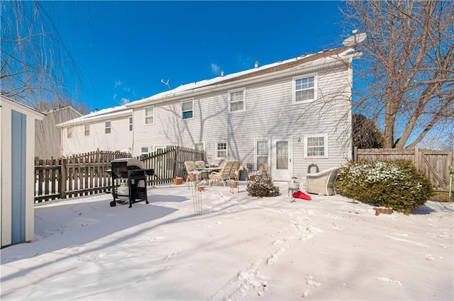 snow covered rear of property with a fenced backyard