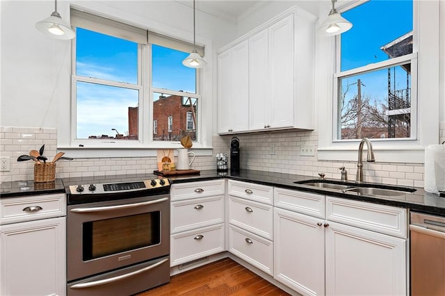 kitchen featuring stainless steel appliances, hanging light fixtures, a sink, and white cabinetry