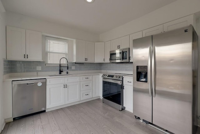 kitchen featuring appliances with stainless steel finishes, white cabinets, light countertops, and a sink