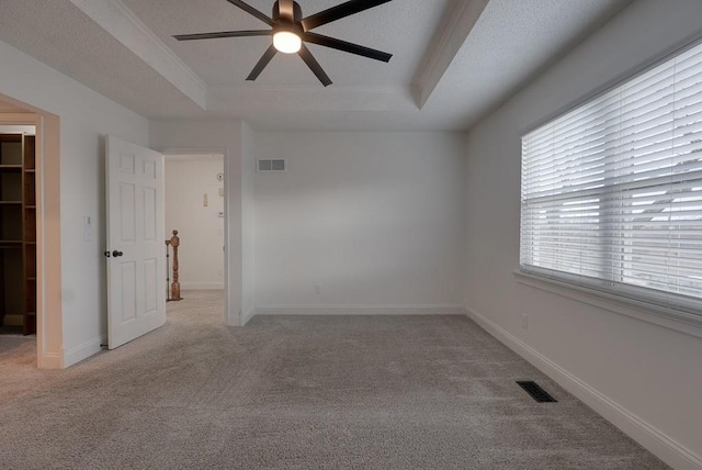 empty room featuring a raised ceiling, visible vents, and baseboards