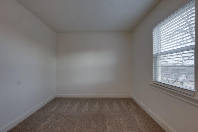 carpeted empty room featuring baseboards