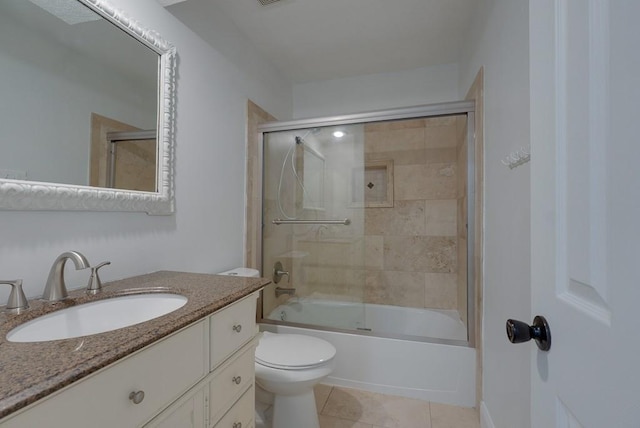 bathroom featuring tile patterned floors, vanity, toilet, and bath / shower combo with glass door