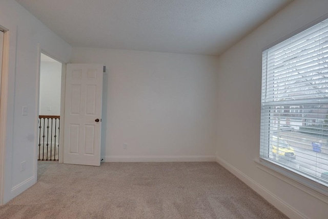 unfurnished room with light colored carpet, a healthy amount of sunlight, and baseboards