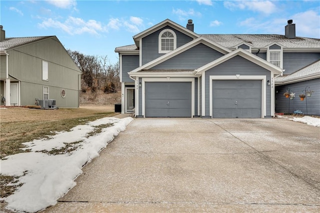 traditional home with central AC unit, an attached garage, and concrete driveway