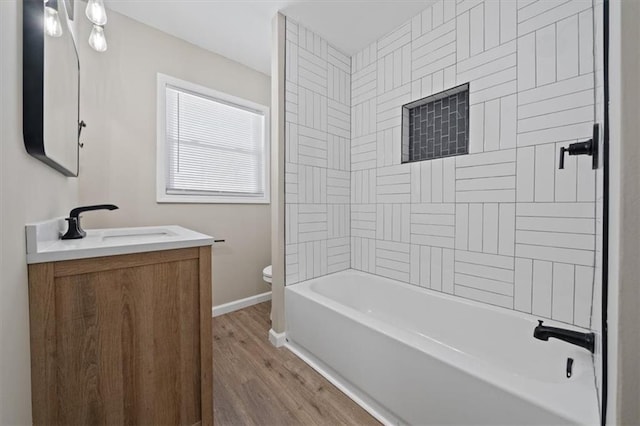 full bathroom with vanity, tiled shower / bath, hardwood / wood-style flooring, and toilet