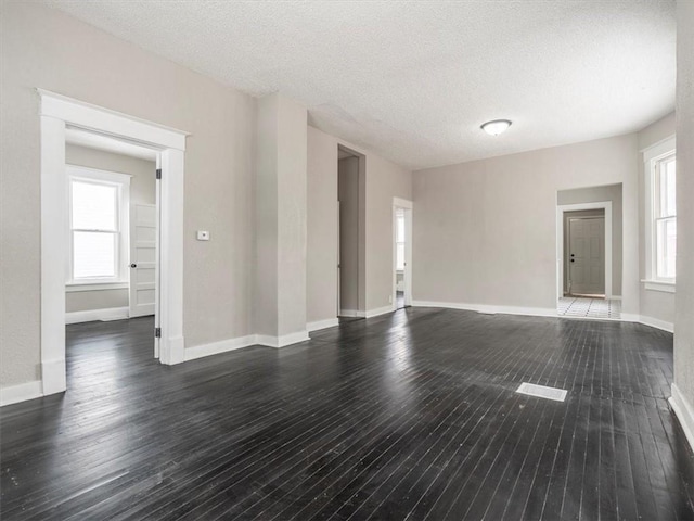 unfurnished living room with a textured ceiling, dark hardwood / wood-style floors, and a healthy amount of sunlight